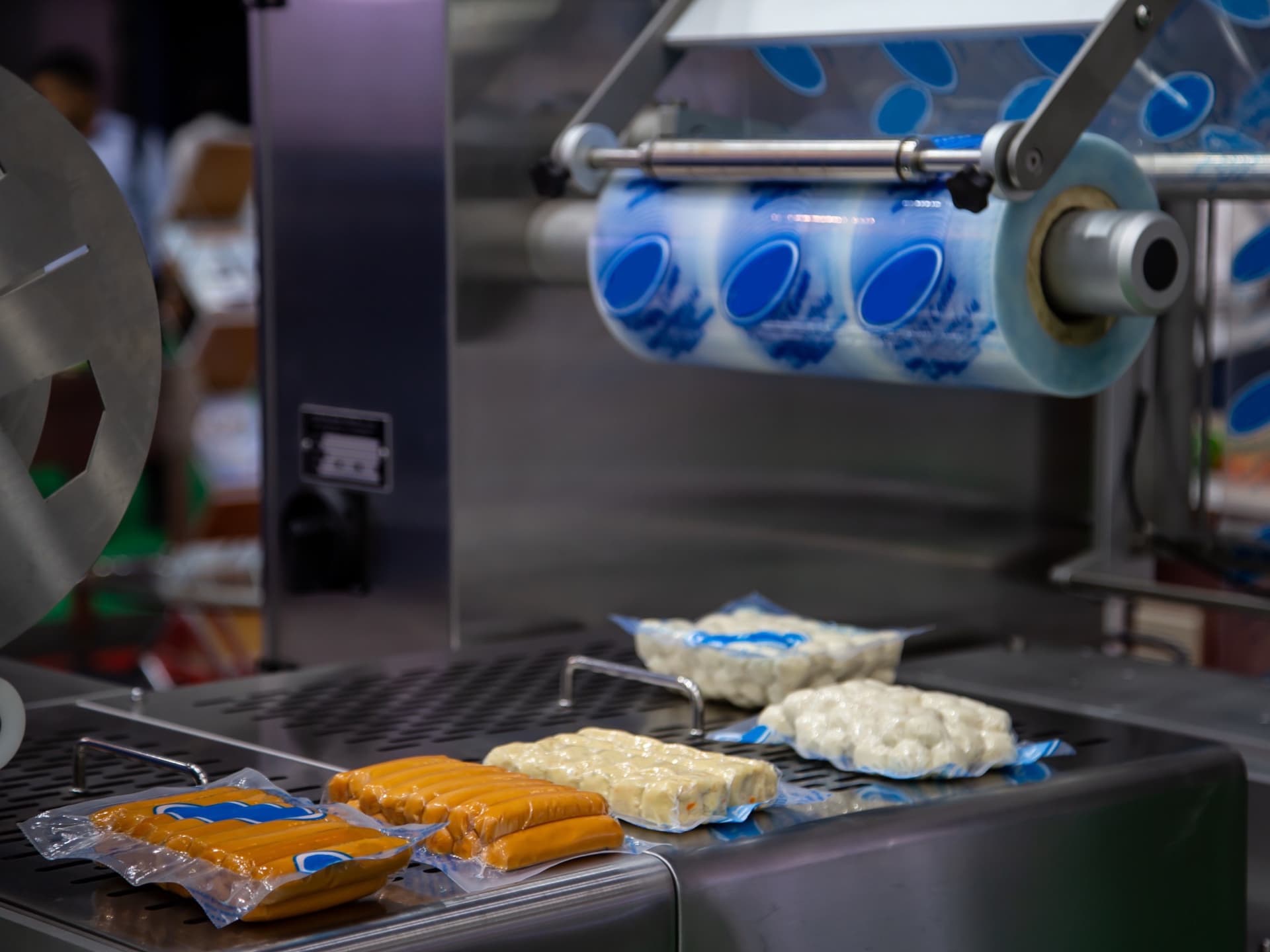 Vacuum-sealed food packs on a tray-sealing machine in a packaging line