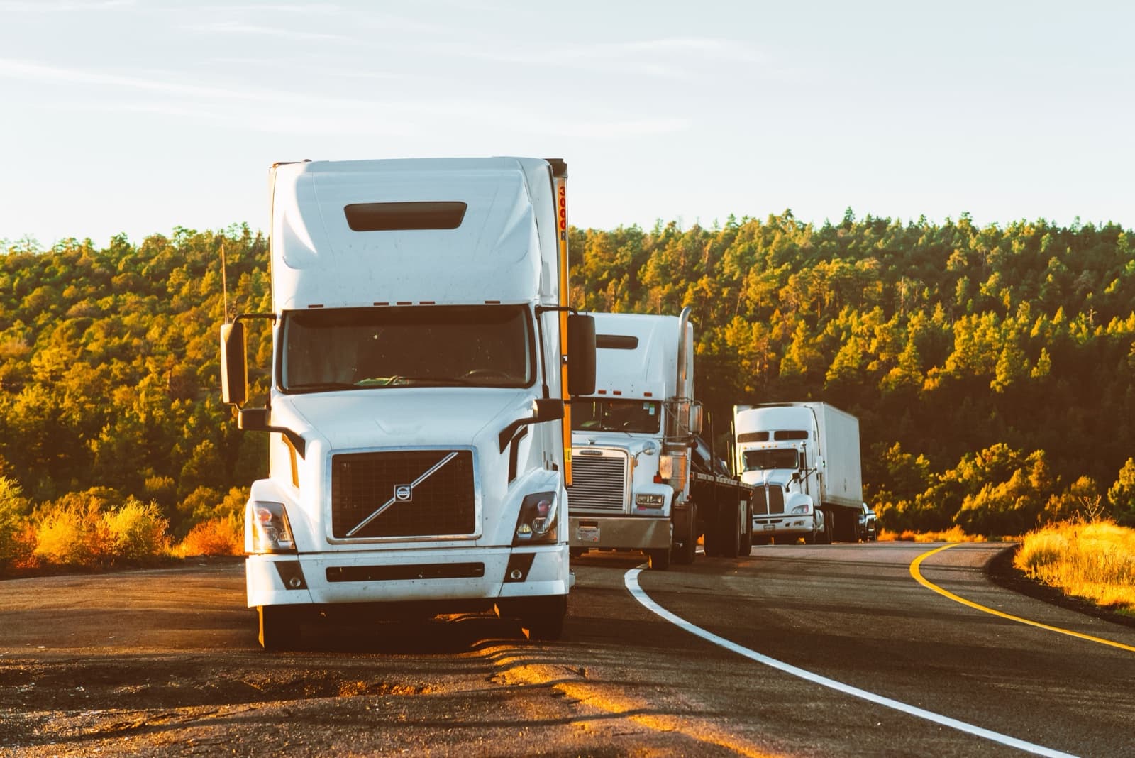 Convoy of semi-trucks on a highway at golden hour — food supply chain logistics